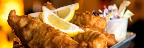 Holding a plate of Fish and Chips with coleslaw and fries