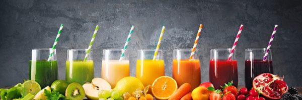 Panoramic food background with assortment of fresh fruits and vegetables juices in rainbow colors