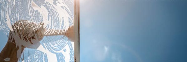 Window cleaner using a squeegee to wash a window with clear blue sky