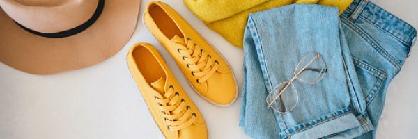 Flat lay with woman's clothes and accessories: jeans, sneakers, sweater and fedora hat