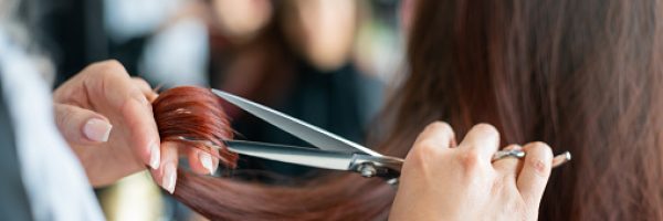 Close up of unrecognizable hairdresser cutting a female customerâs hair - Small business concepts