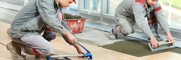 Two industrial tiler builder worker installing floor tile at repair renovation work