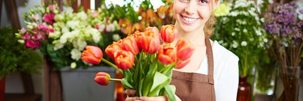 Portrait of young female florist with red tulips looking at camera