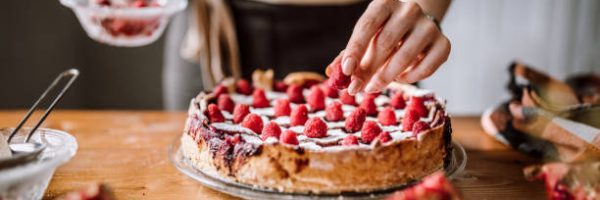 Woman Putting Raspberries To American Blackberry Pie, While It Is In  Mold